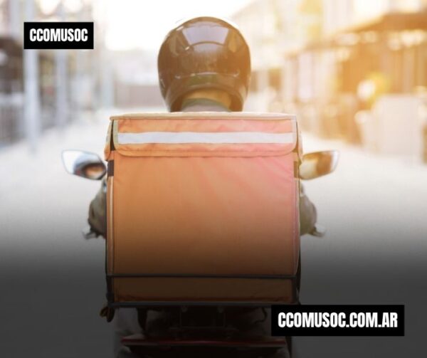 Repartidor en moto visto desde atrás con una mochila térmica naranja y el logotipo de CCOMUSOC