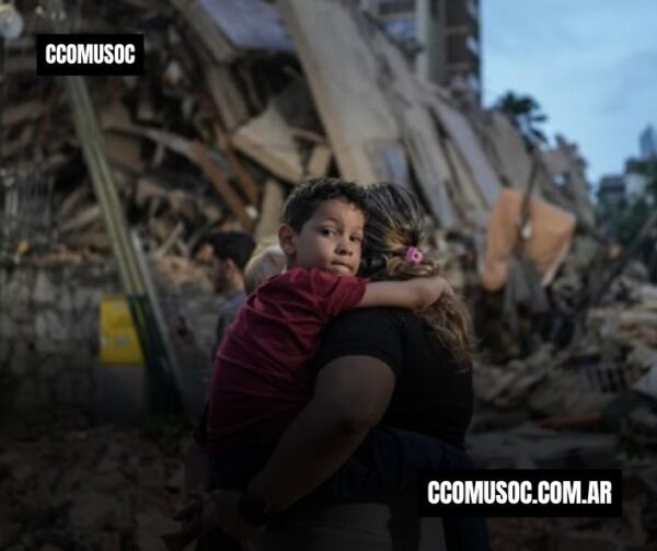 Una mujer sostiene a un niño frente a un edificio derrumbado tras un desastre