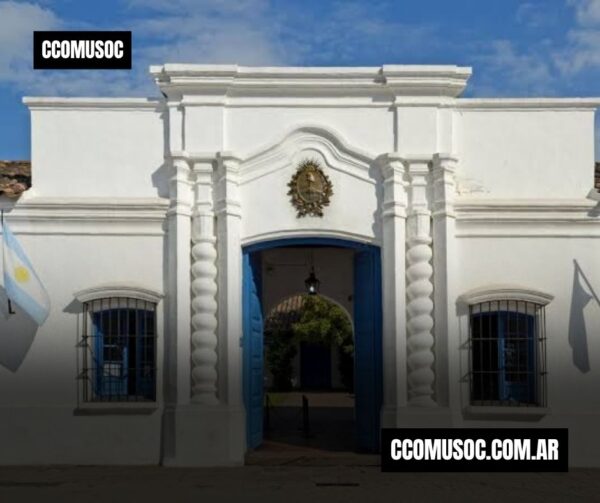 Fachada de la casita colonial de tucumán con puerta azul y escudo argentino en el centro