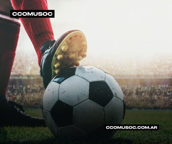Balón de fútbol en el campo con un jugador a punto de patearlo en un estadio lleno