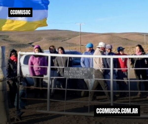 Comunidad reunida junto a una camioneta y una bandera en un paisaje rural